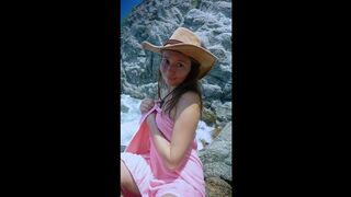 This beauty smiles topless by the rocky shore ?