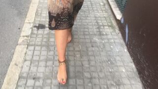 young female hippie is walking barefoot in public street