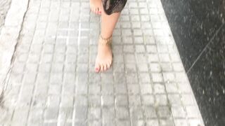 young female hippie is walking barefoot in public street