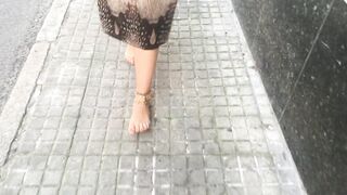 young female hippie is walking barefoot in public street
