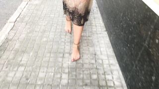 young female hippie is walking barefoot in public street