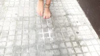 young female hippie is walking barefoot in public street