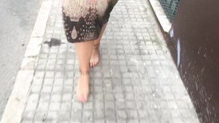 young female hippie is walking barefoot in public street