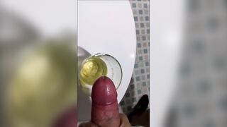 A dude in sweatpants pisses and cums in a glass for his friend, who then drinks it